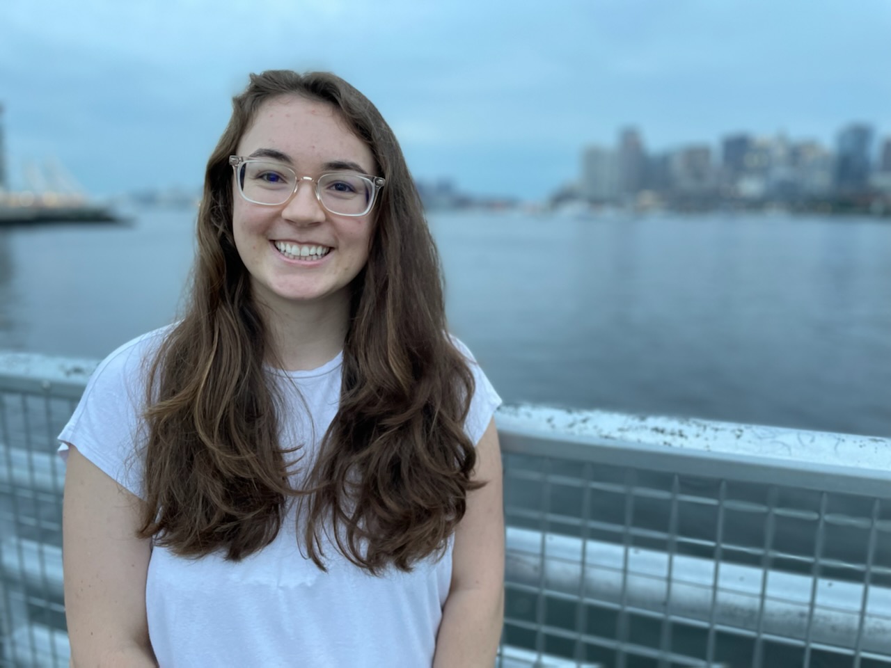 *Caption: Sarah standing in front of the Boston Harbor with a smile.*